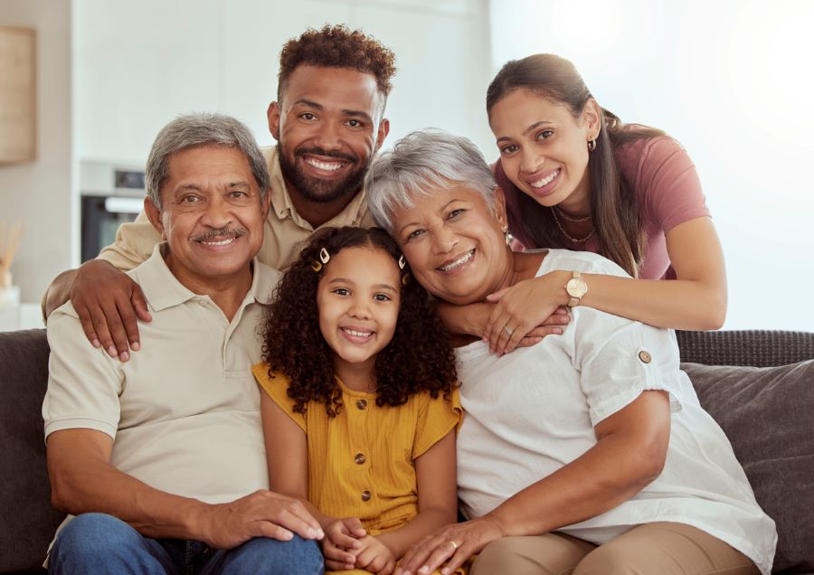 Portrait of mixed race extended family with child enjoying weekend in living room at home