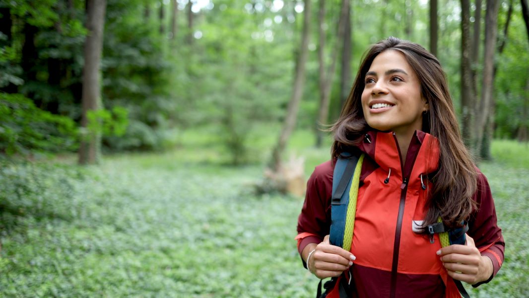 a young latina woman with long hair hiking in a forest