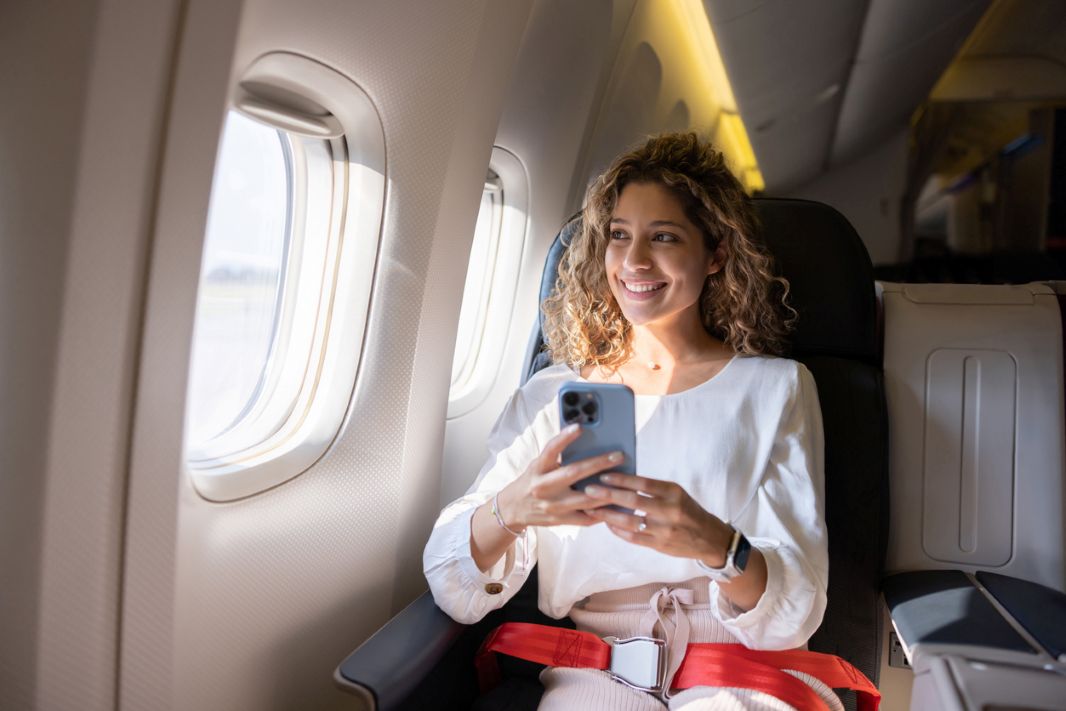 female traveler using her cell phone in an airplane