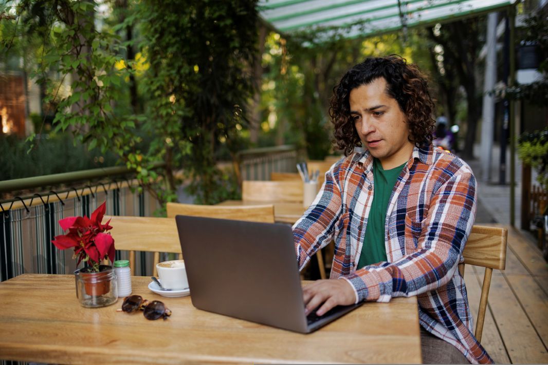 Hispanic young man outdoors using laptop